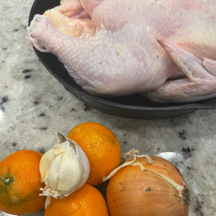 whole chicken raw with onion, garlic and oranges